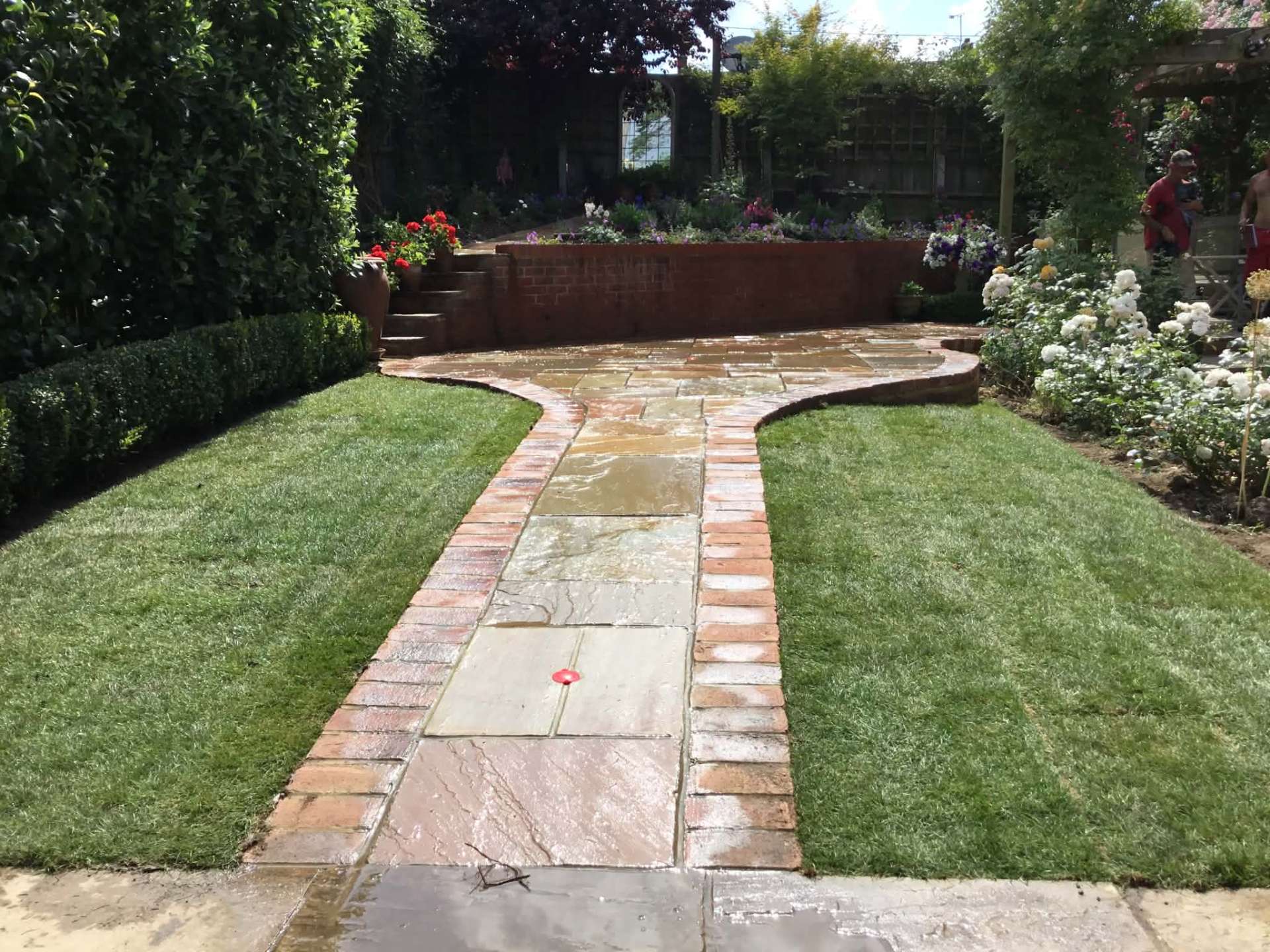 Sandstone garden path with brick edging and rose borders