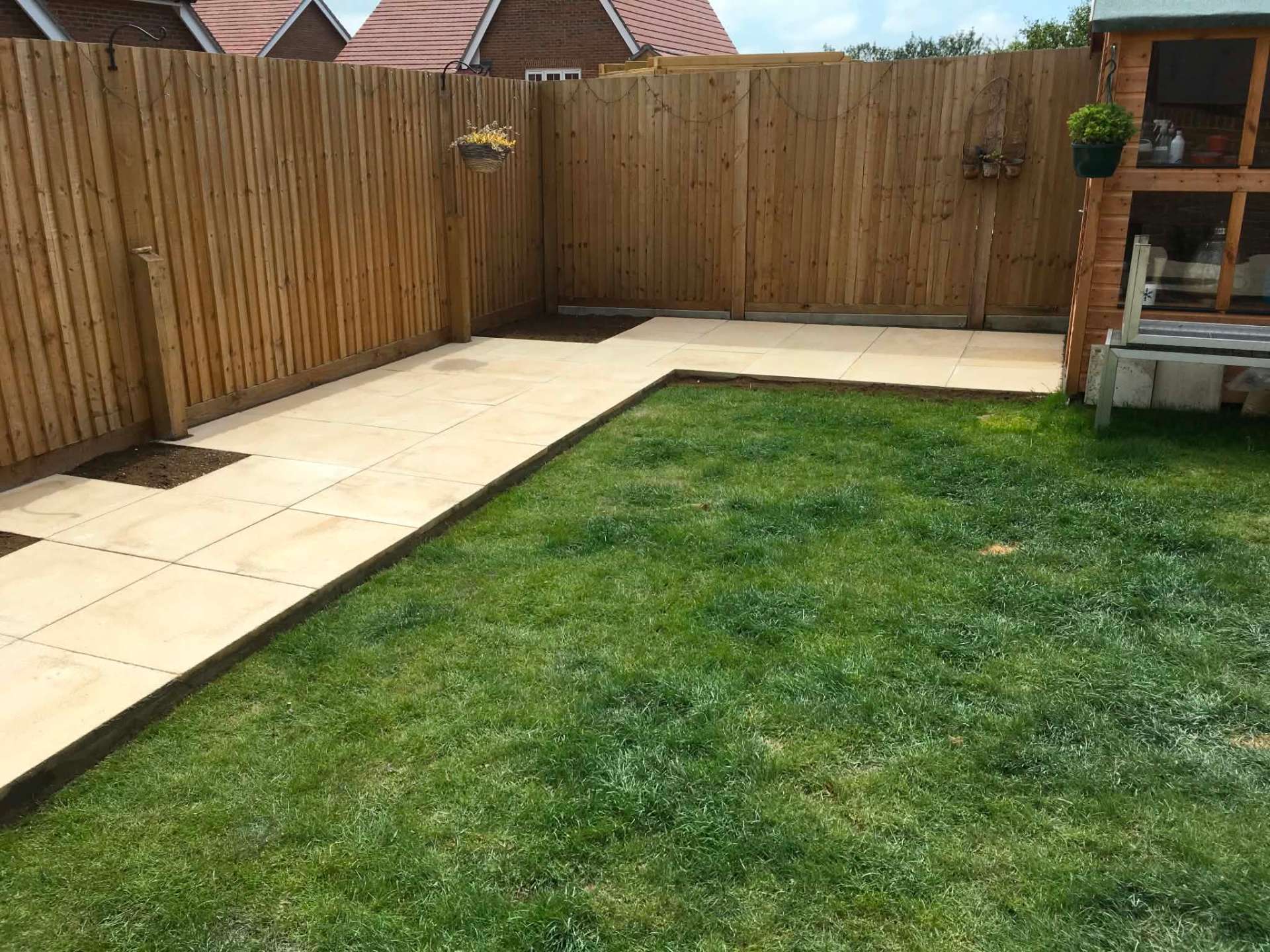 New sandstone patio with fresh lawn and timber fencing
