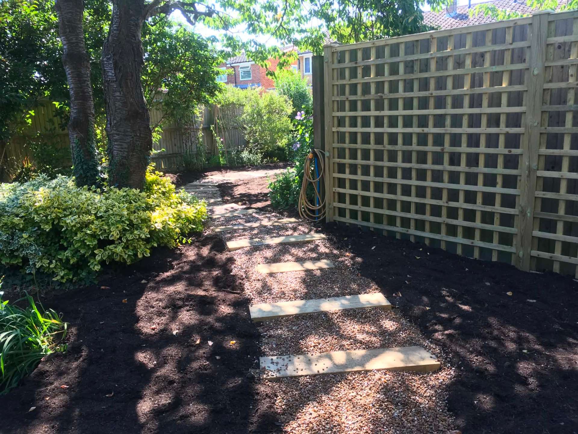 Sleeper stepping-stone path through shaded border with trellis