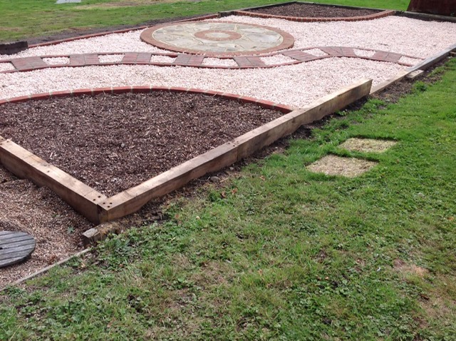Gravel garden with brick-edged beds and circular sandstone feature