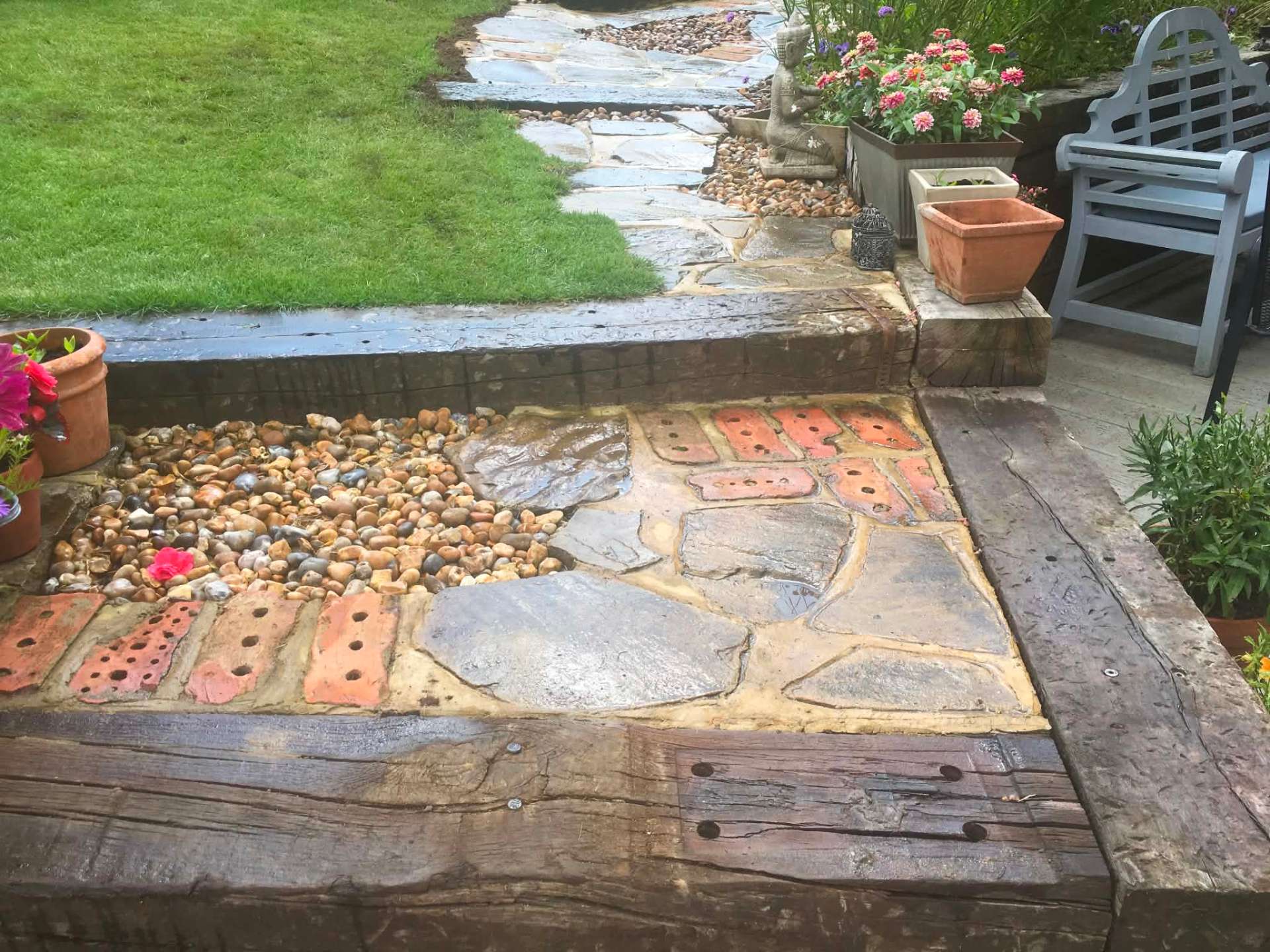Crazy paving path with pebble inlay and railway sleeper steps