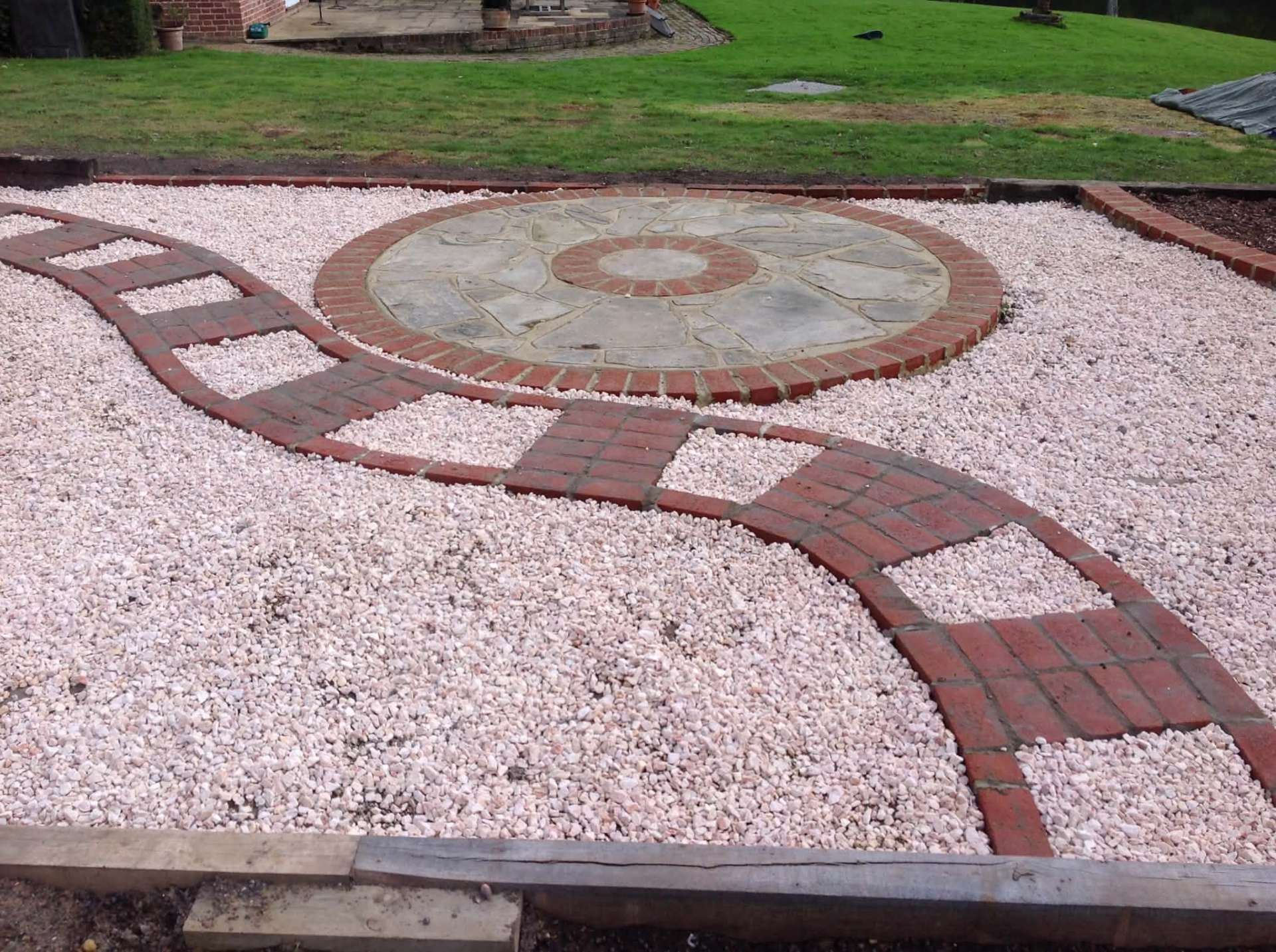 Decorative gravel garden with circular paved centrepiece and brick paths
