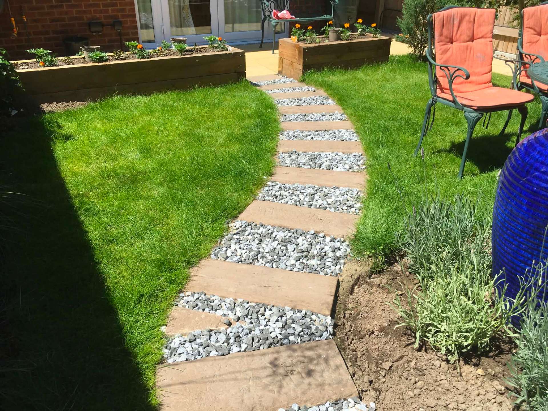 Curving sleeper and gravel stepping path through fresh lawn