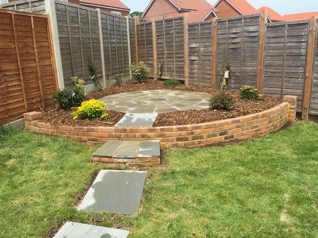 Curved brick raised bed with sandstone circle and stepping-stone lawn path