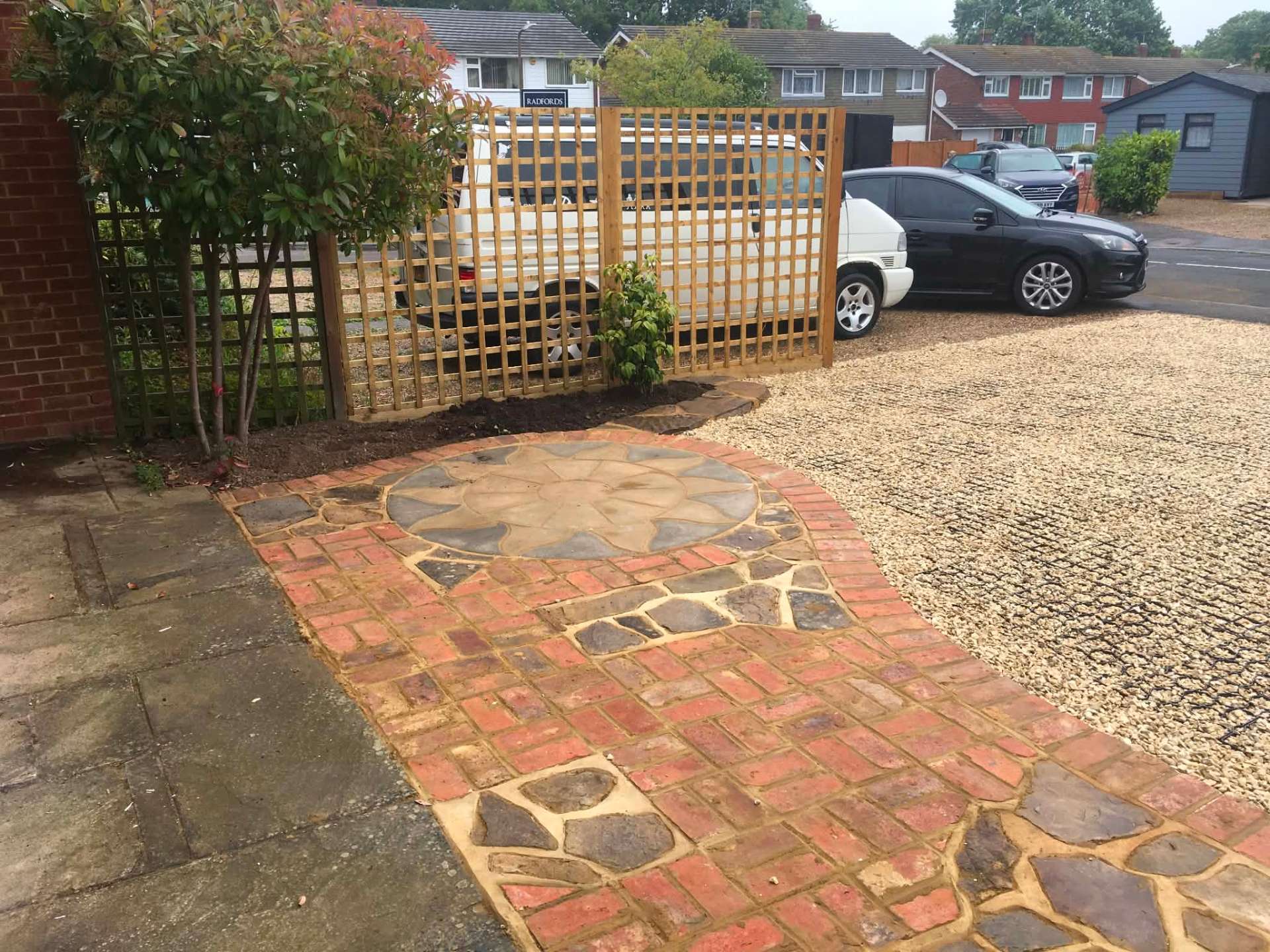 Reclaimed brick and crazy-paving driveway with sun-pattern stone circle