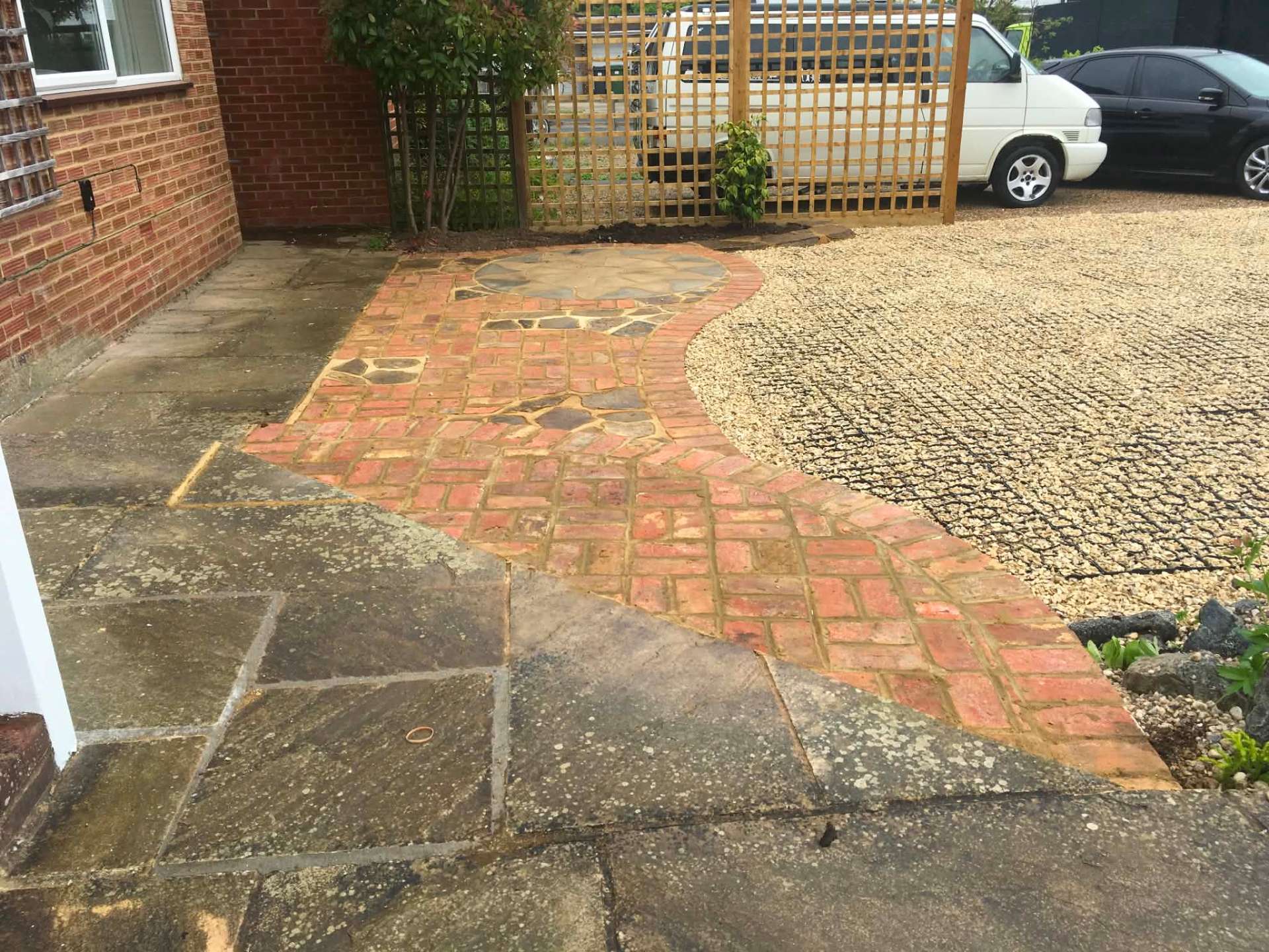 Curving brick and flagstone path meeting gravel driveway