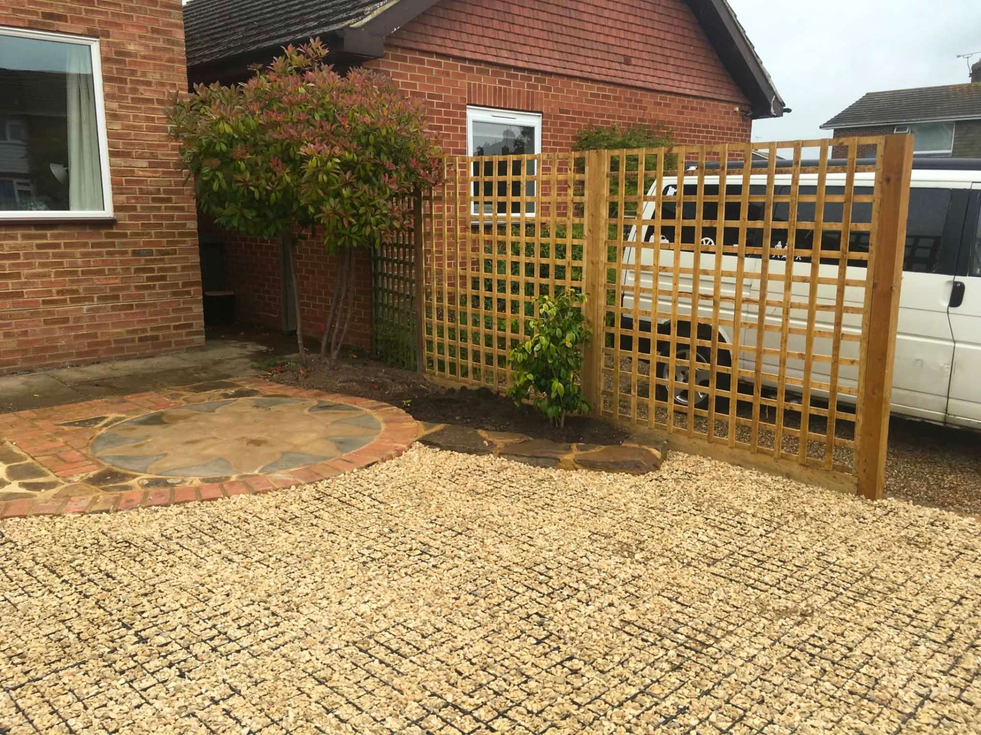 Gravel grid driveway with sandstone circle and timber trellis screen