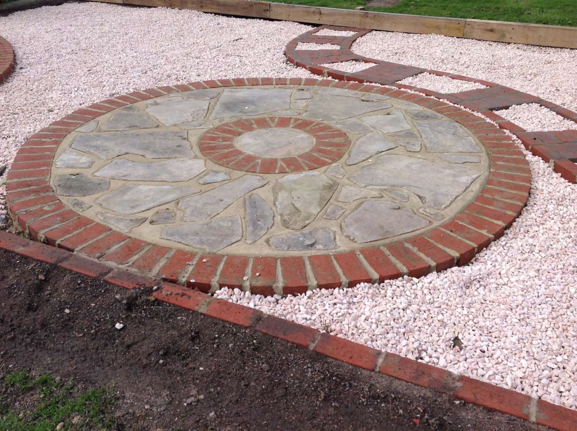 Reclaimed stone and brick circle set in white gravel garden